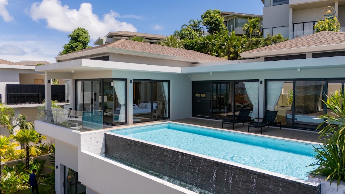 Aerial view of a hillside villa with infinity pool and tropical garden