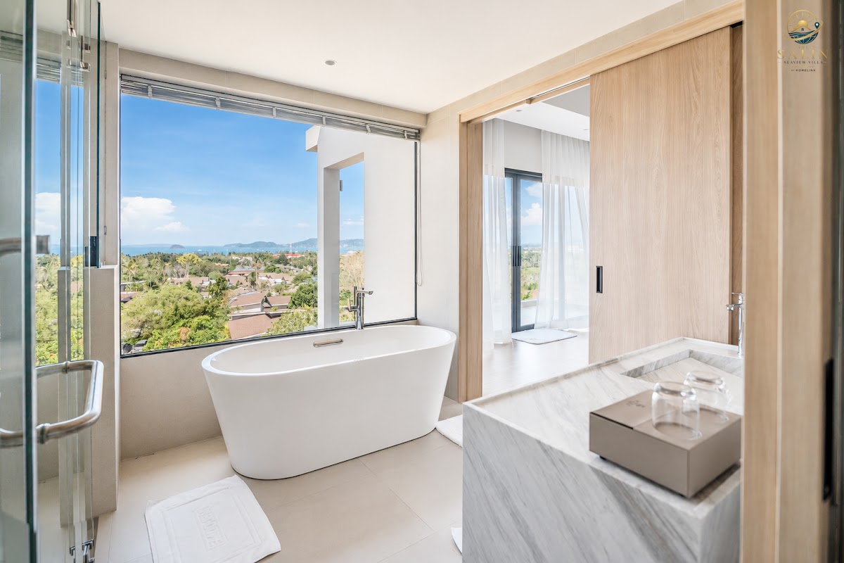 Freestanding bathtub beside a window framing the tropical hills