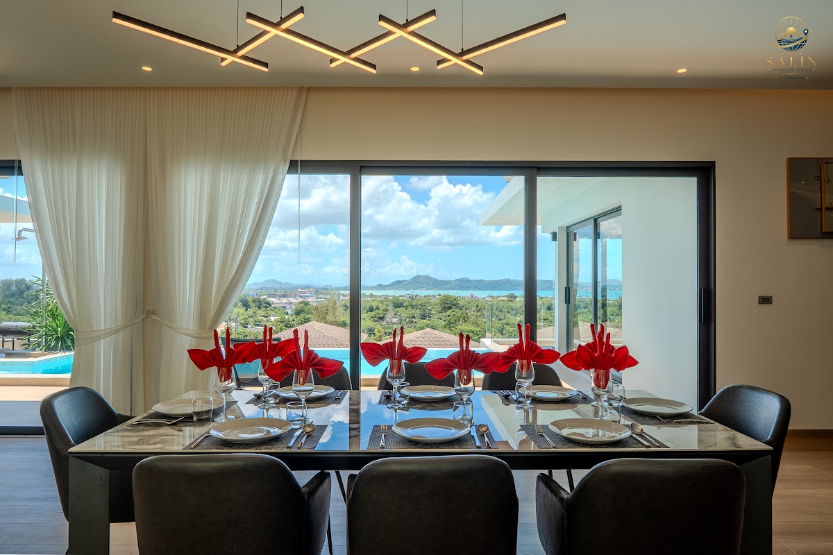 Dining table set for guests with sea view through full-height glass